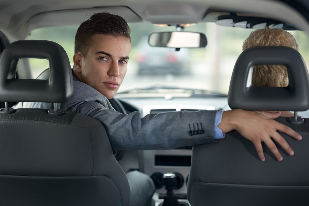 Kierowca w garniturze cofający auto, patrzy przez tylną szybę