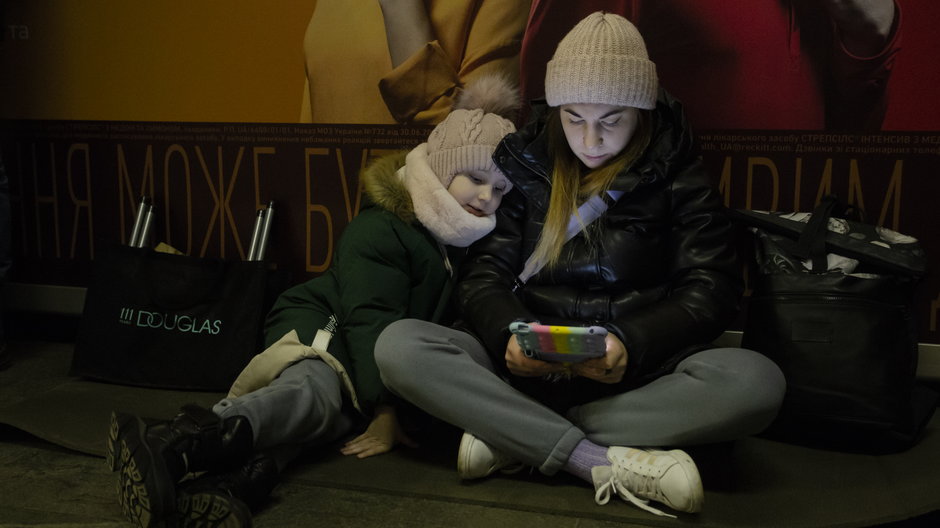 Kobieta i dziecko chowające się na stacji metra podczas alarmu w Kijowie, 10 lutego 2023 r.