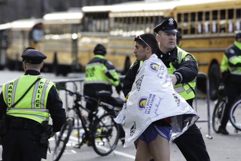 Policja pomaga jednemu z maratończyków po zamachu w Bostonie