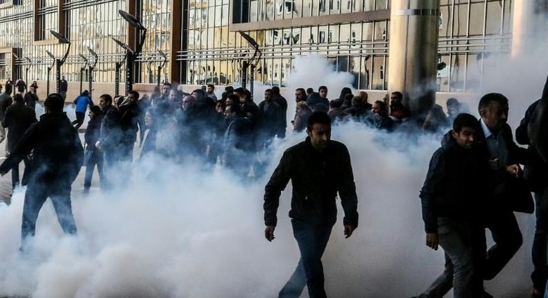 Demonstrators walk away as Turkish riot police use tear gas and water cannon to disperse protestors outside the municipalty headquarters in Van, eastern Turkey on November 17, 2016