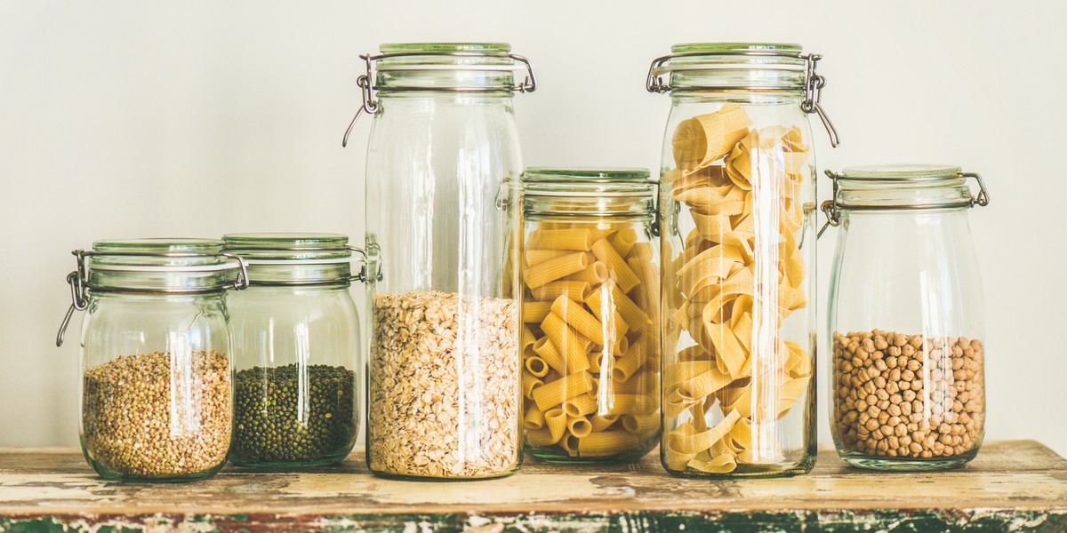 Uncooked cereals, grains, beans and pasta in jars on table