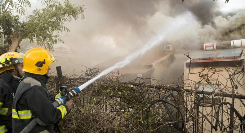 Israeli firefighters help extinguish a fire in the northern Israeli port city of Haifa on November 24, 2016