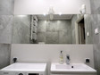 Duże płyty dodające ścianom majestatu, szerokie lustro, proste formy nierozbijające optycznie przestrzeni sprawiają wrażenie, że łazienka jest przestronna. 