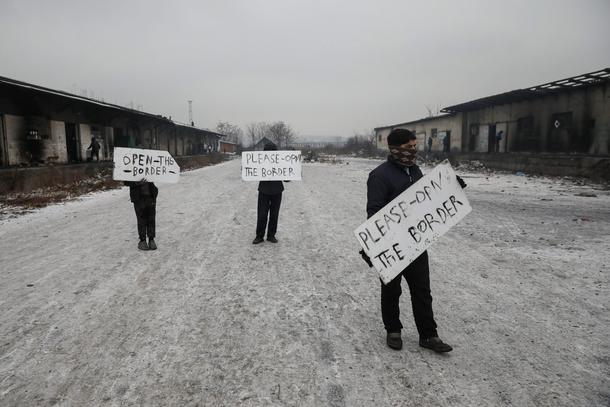 Migrants hold placards during a protest outside a derelict customs warehouse in Belgrade