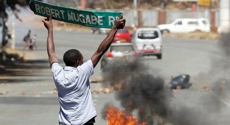 A man carries a street sign as opposition party supporters clash with police in Harare, Zimbabwe, August 26,2016.