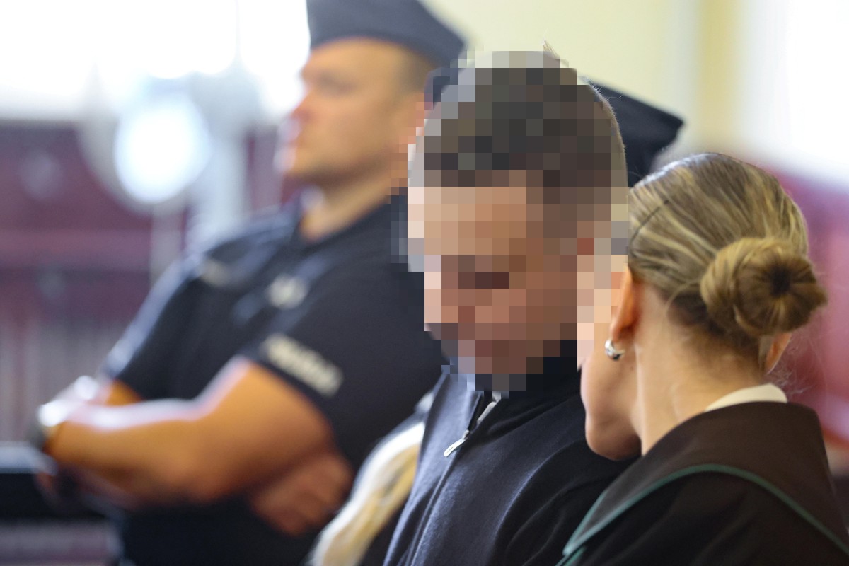 Oskarżony Sebastian M., mężczyzna z siedzi na sali sądowej obok obrońcy, w tle widoczny policjant