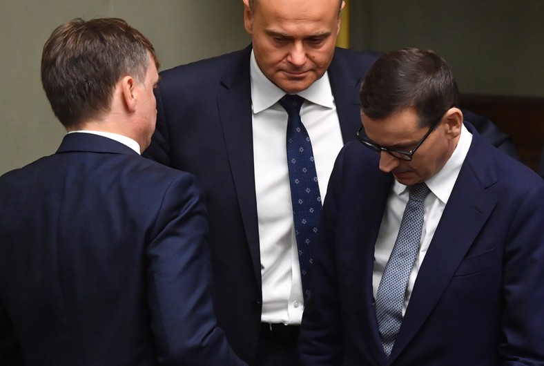 Premier Mateusz Morawiecki (P), minister sprawiedliwości, prokurator generalny Zbigniew Ziobro (L-tyłem) oraz poseł PiS Andrzej Kosztowniak (C) na sali obrad Sejmu w Warszawie