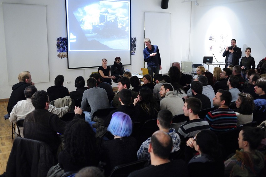 Otvoreno predavanje NOOR-a u prepunoj galeriji "KC grad-a"   Kadir Van Lohuizen u ulozi moderatora otvorio je predavanje fotografa NOOR-a, Andree Brus i Stenlija Grina. Njih dvoje su prikazivali fotografije i pričali o svojim iskustvima sa suprotnih strana u ratu u Siriji.