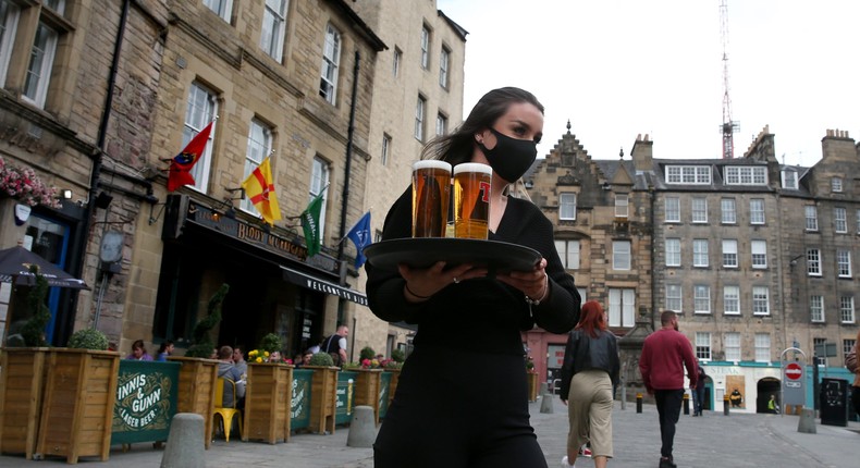 A server carries a tray of drinks from a pub in Edinburgh, Scotland, on April 26, 2021.
