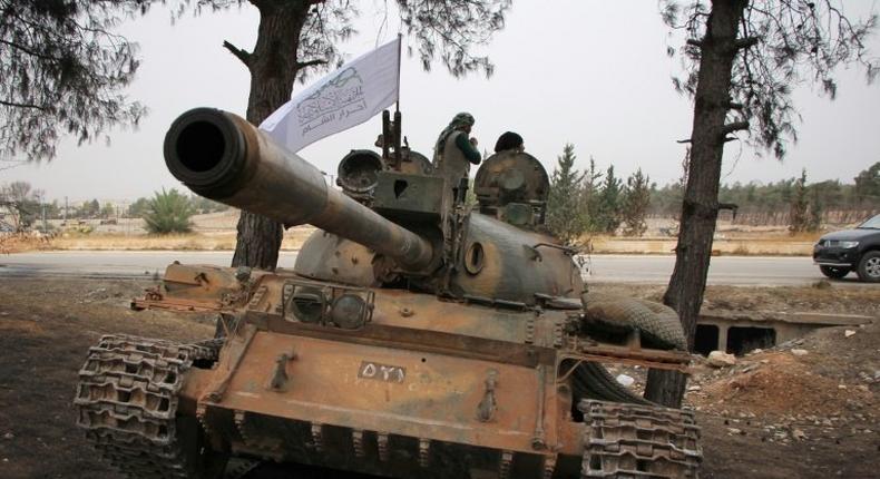 Syrian rebel fighters from the Jaish al-Fatah (or Army of Conquest) stand on a T-55 tank as they hold a position on the outskirts of Aleppo in October 2016