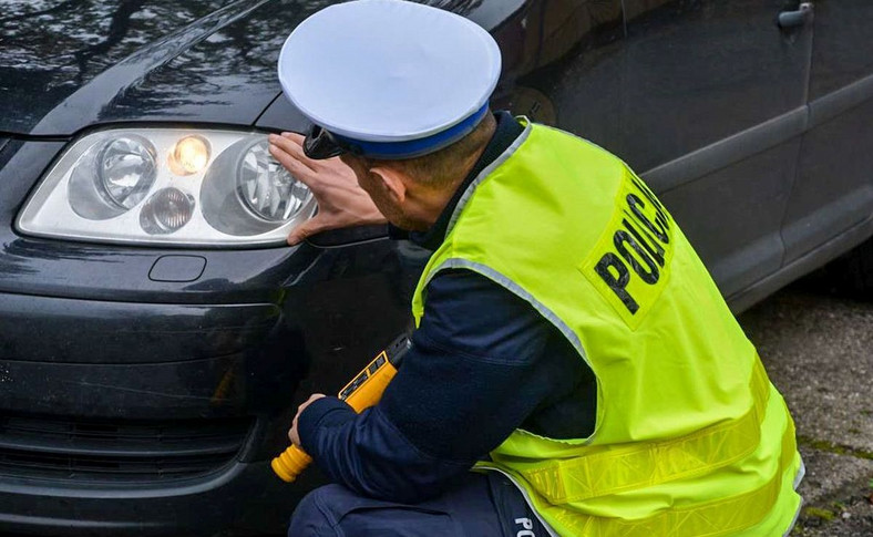 Policjant kontroluje stan oświetlenia w samochodzie