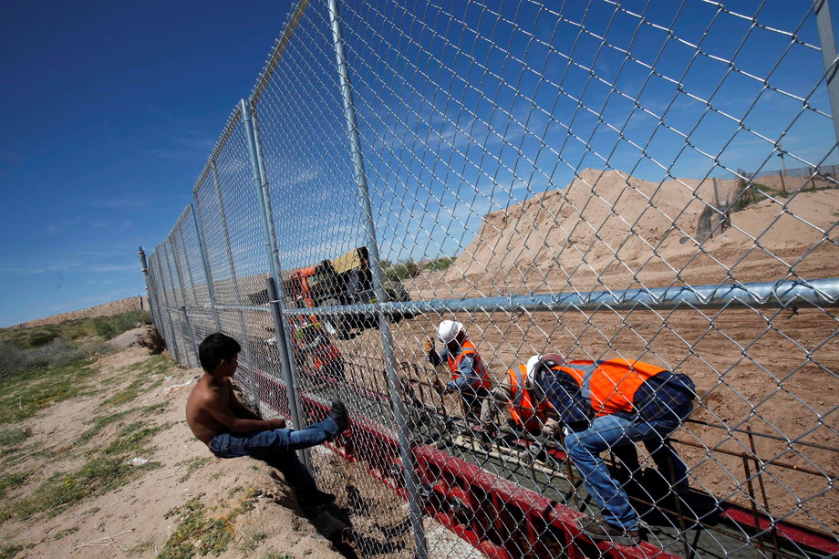 A boy watching US workers build a section of a US-Mexico border wall.