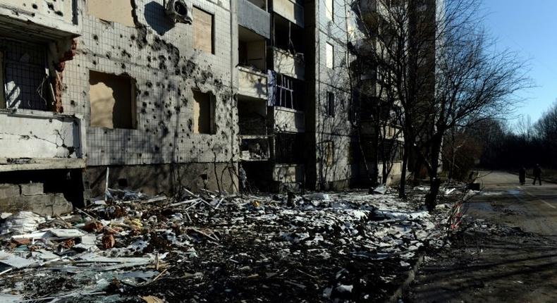 Pedestrians walk past a damaged building in Donetsk