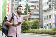 Young White Man Holding A Cellphone Hailing Uber Taxi