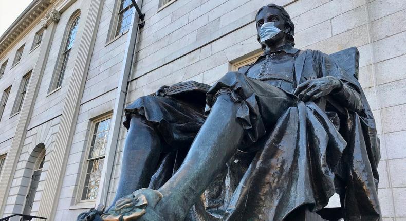 The John Harvard statue at Harvard University adorned with a face mask.