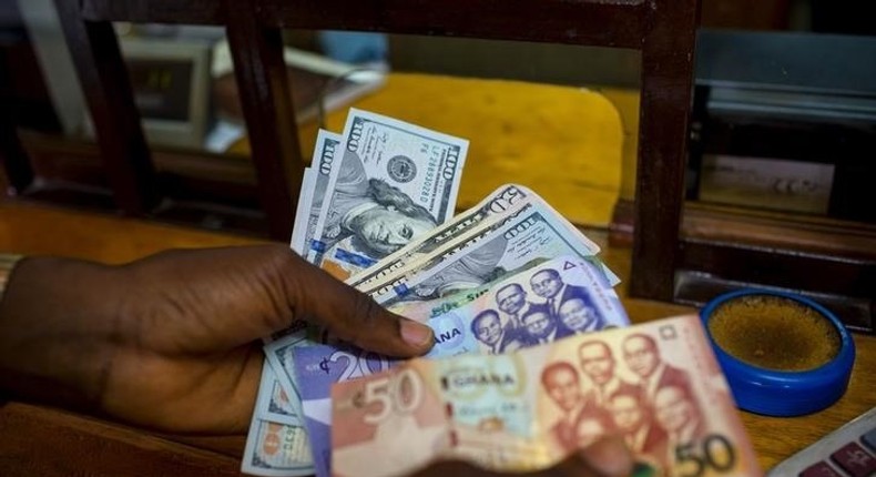 A man trades U.S. dollars for Ghanaian cedis at a currency exchange office in Accra, Ghana, June 15, 2015. Picture taken June 15. REUTERS/Francis Kokoroko