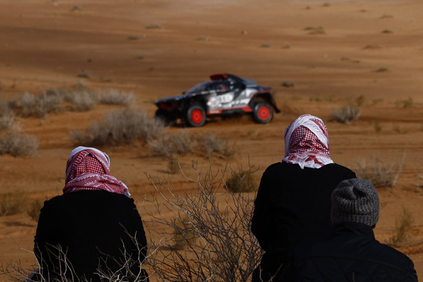 Kibice na trasie etapu 1B tegorocznego Rajdu Dakar; w tle Carlos Sainz za kierownicą Audi