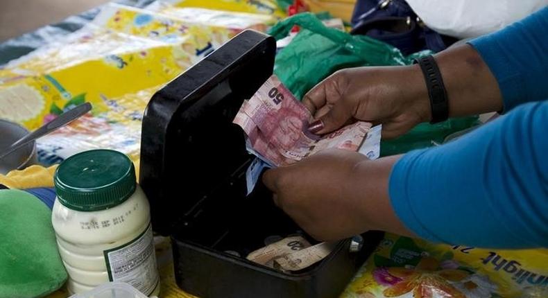 An informal trader counts out change in her cash box at her stall in Hillcrest, west of Durban, South Africa, January 11, 2016. 