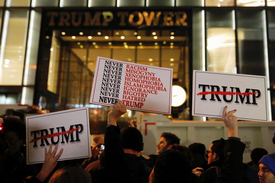 Demonstrators hold signs outside Trump Tower during a protest march against President-elect Donald Trump in Manhattan, New York, U.S. November 9, 2016.