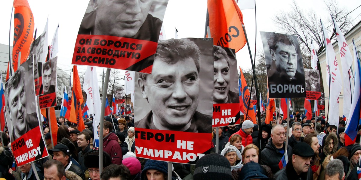 People hold flags and posters during a march to commemorate Kremlin critic Boris Nemtsov, who was shot dead on Friday night in central Moscow on March 1, 2015.