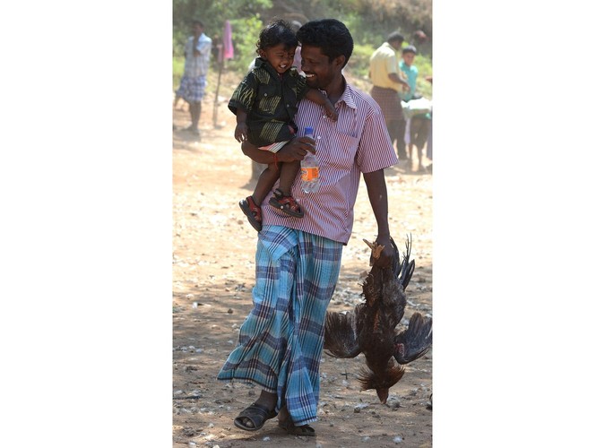 Ojciec, dziecko i zawodnik, który przegrał walkę. Zdjęcie wykonane w wiosce Poolamvalasu w Indiach