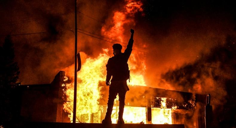 Un manifestant devant un bâtiment incendie dans la ville américaine de Minneapolis dans la nuit du 29 au 30 mai 2020