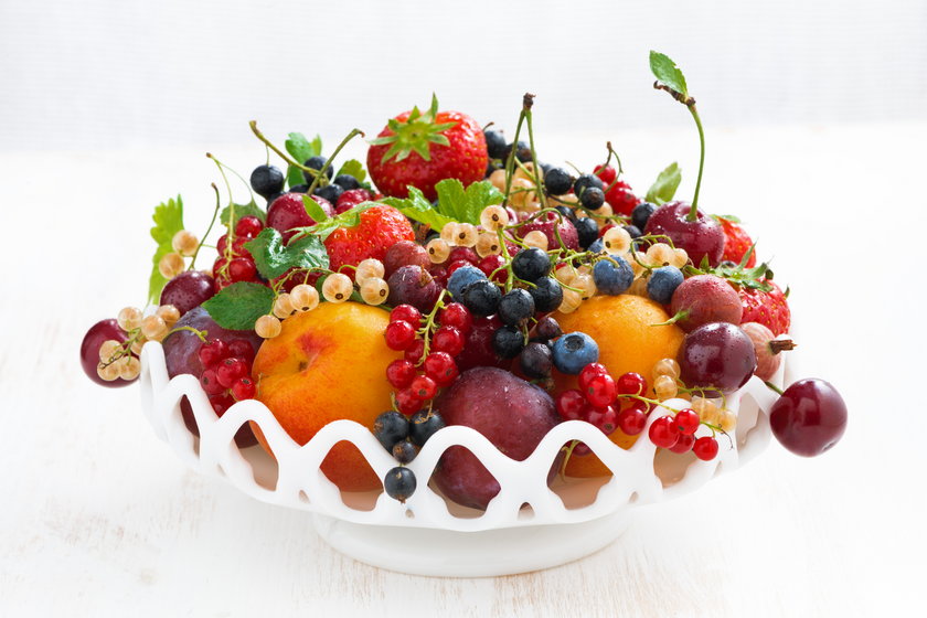 dish with seasonal fruit and berries on white table