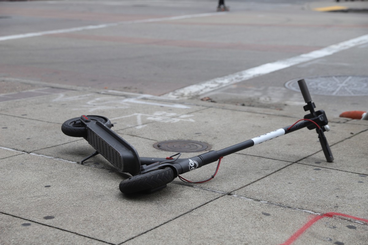 Porzucona hulajnoga elektryczna na chodniku