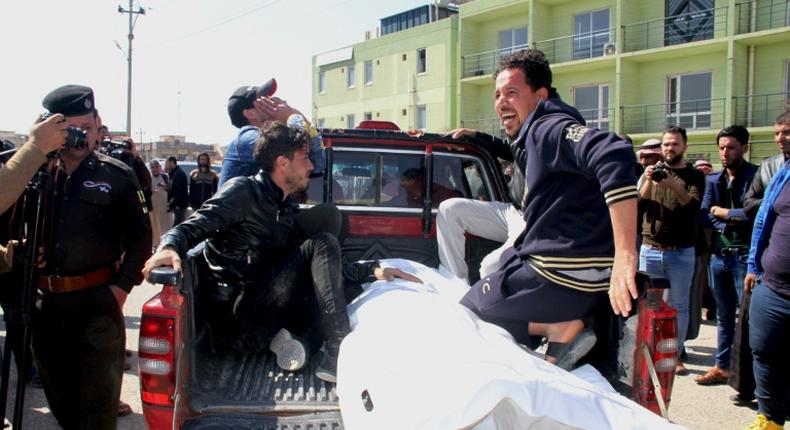 Relatives mourn over the body of a passenger who died in a ferry accident while crossing the Tigris river outside a morgue in the northern Iraqi city of Mosul