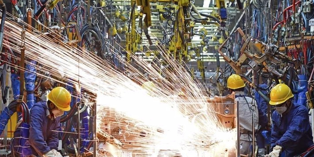 Employees work along a production line at a factory of Dongfeng Nissan Passenger Vehicle Co. in Zhengzhou