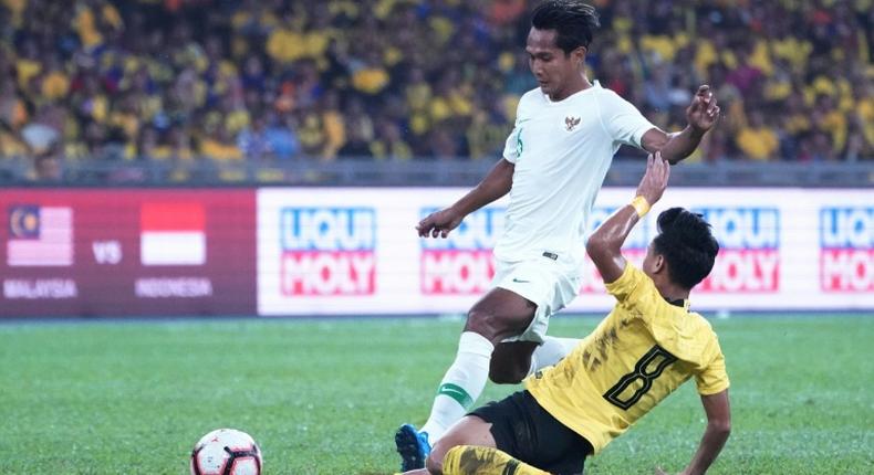 Malaysia's Muhamad Nor Azam  tries to escape a tackle from Indonesia's Hendro Siswanto in  as the home team win Kuala Lumpur