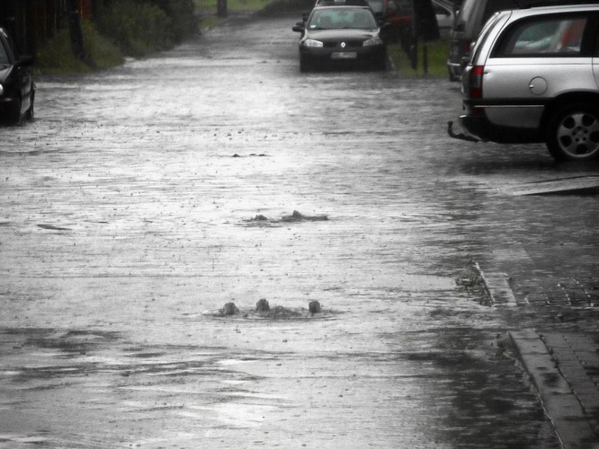 Zatopione ulice Warszawy po burzy z gwałtownym oberwaniem chmury. Woda wybijająca ze studzienek.