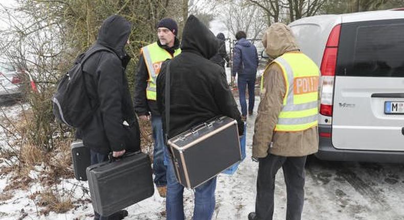 Police officers and forensics walk towards the premises where the deaths occured