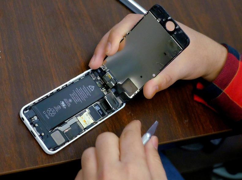 FILE PHOTO: A man tries to repair an iPhone at a repair shop in New York