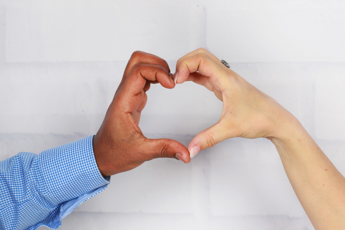 Czarny mężczyzna i biała kobieta składają dłonie w serce