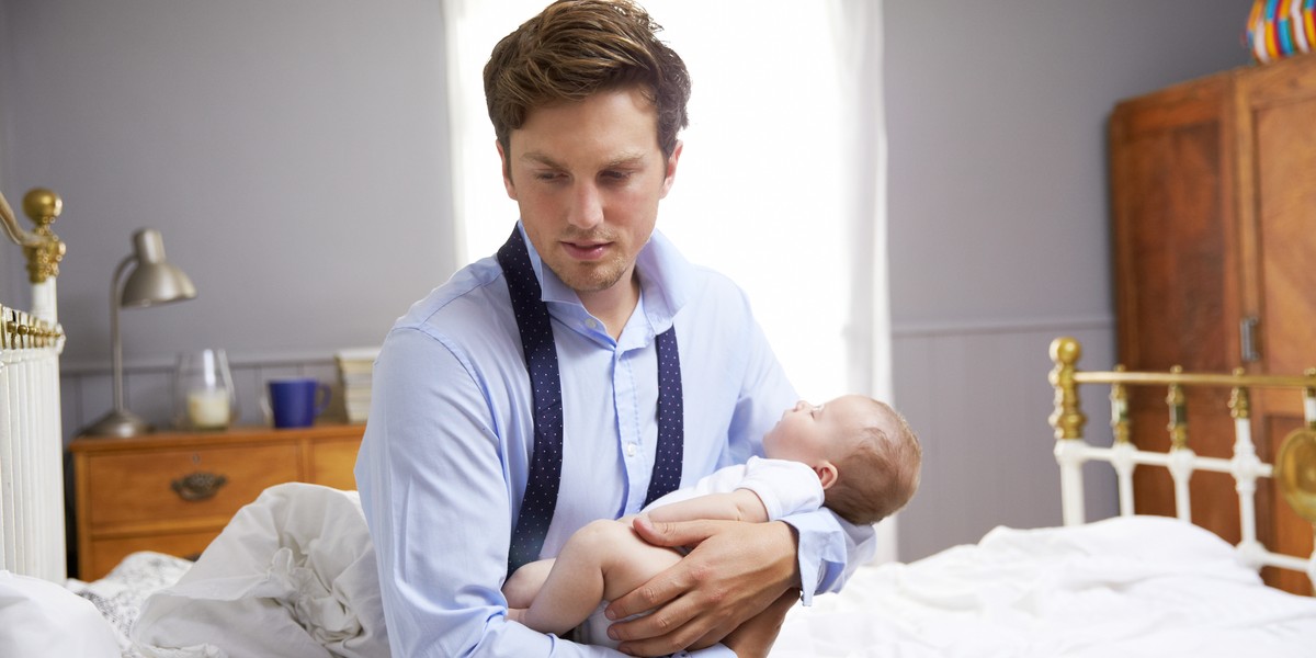 Stressed Father Dressed For Work Holding Baby In Bedroom