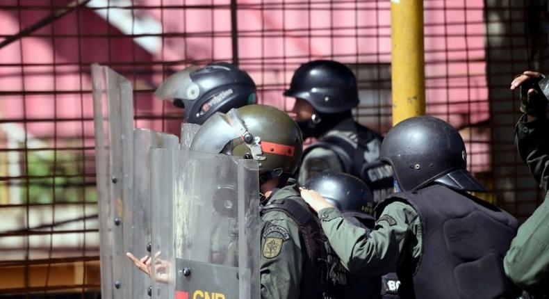 Venezuelan national guard officers in riot gear protect themselves during Friday's protest against President Nicolas Maduro's government