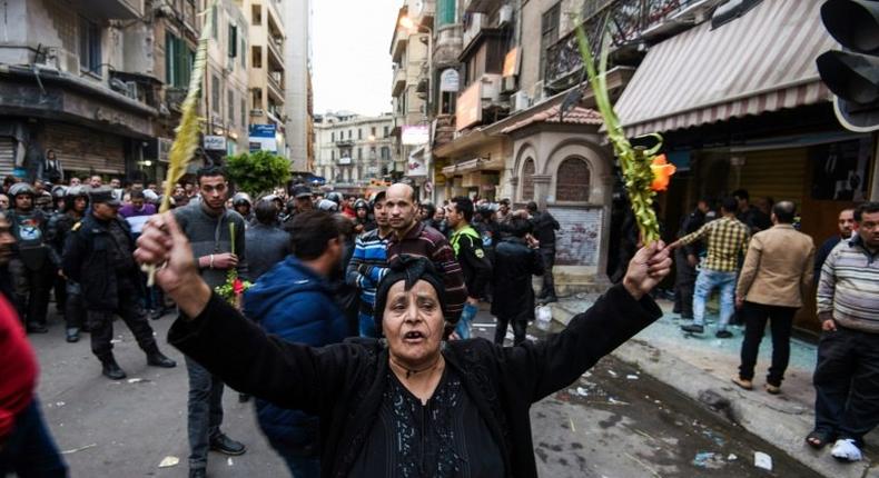 An Egyptian woman raises braided palm leaves, originally intended for Palm Sunday celebrations, during a gathering outside the Coptic Orthodox Patriarchate in Alexandria after a bomb blast struck outside while worshippers attended Palm Sunday mass on April 9, 2017