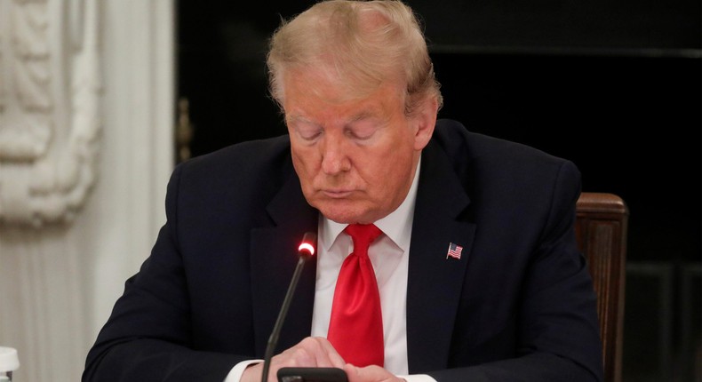 .S. President Donald Trump uses a mobile phone during a roundtable discussion on the reopening of small businesses in the State Dining Room at the White House in Washington, U.S., June 18, 2020.