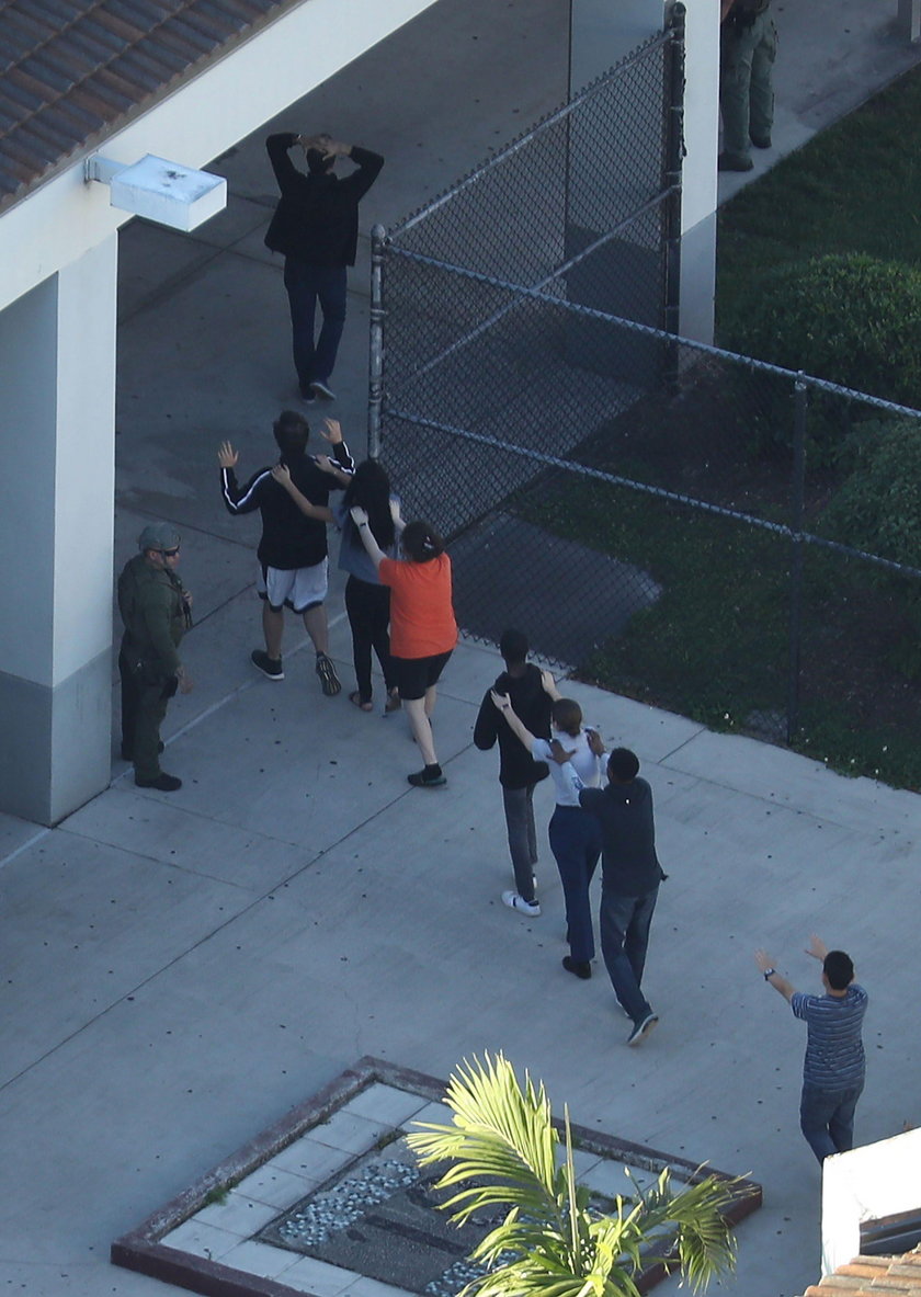 Police escort a suspect into the Broward Jail after checking him at the hospital following a shootin