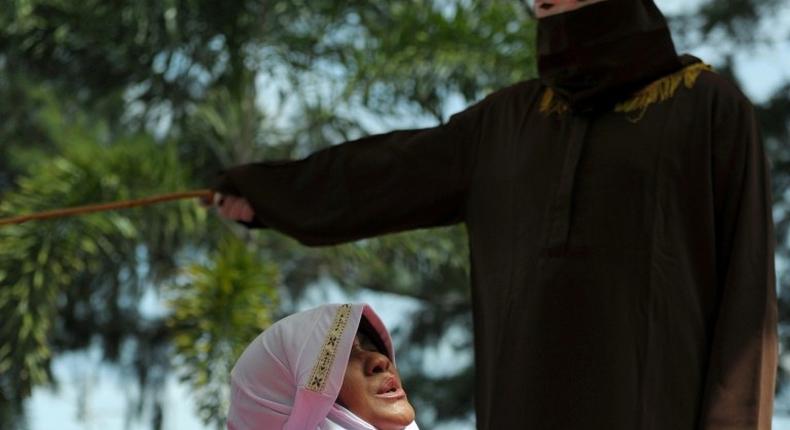 A religious officer canes a woman for spending time in close proximity with a man who is not her husband in Banda Aceh, Indonesia, on November 28, 2016