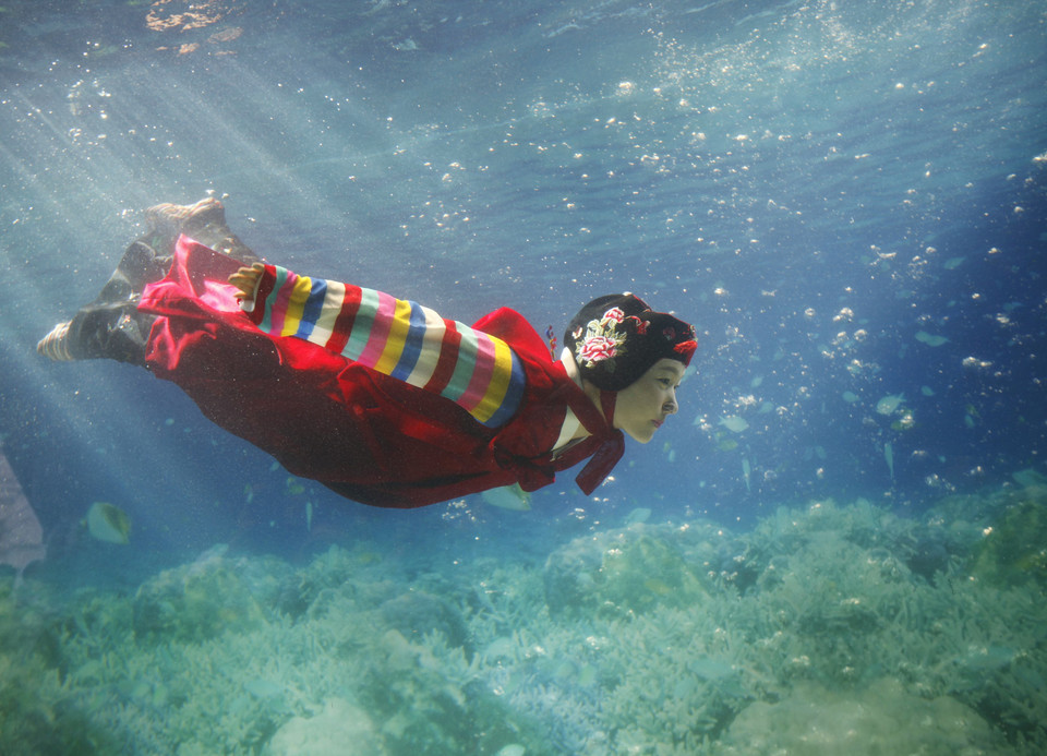 A promoter wearing a traditional hanbok performs in a water tank at the "Underwater Hanbok Fashion Show" during a photo call in Seoul