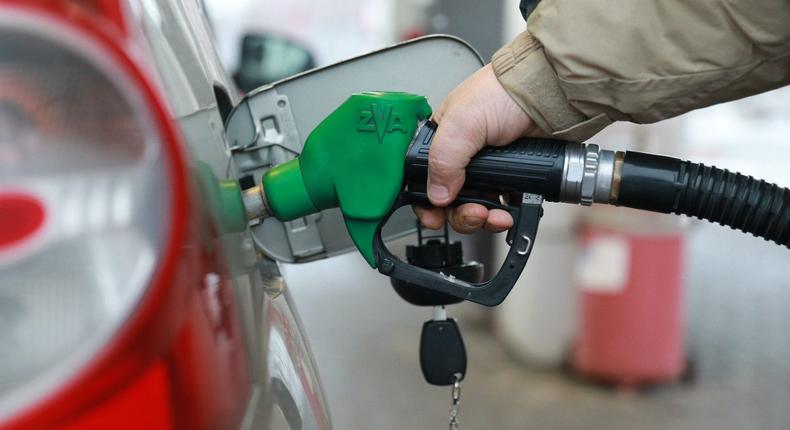 A man fills up a car at a filling station.
