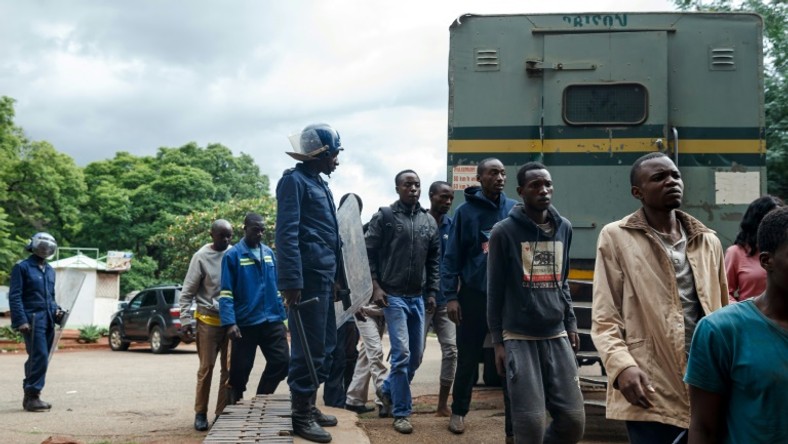 Zimbabwean anti-riot police forces watch men arrested during violent protests triggered by a sudden rise in fuel prices announced by Zimbabwean president, before their hearing at the Law Court in Harare on January 16, 2019
