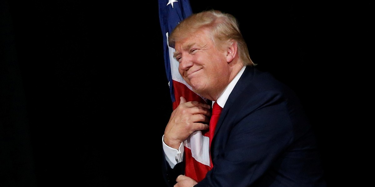 Trump hugs a U.S. flag as he comes onstage to another rally with supporters in Tampa, Florida on October 24.