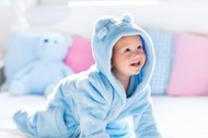 Baby in bathrobe or towel after bath on white bed