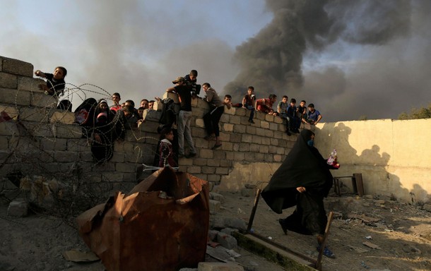 A newly displaced woman runs after she jumped over a back wall and rushed to grab humanitarian packa