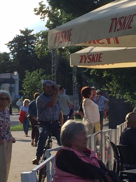 W tłumie dostrzegam mężczyznę, który przyjechał na rowerze, a na szyi ma... lornetkę