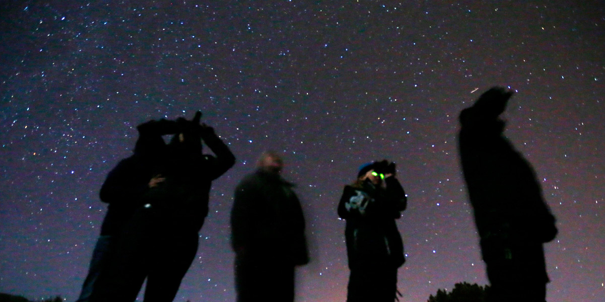 People use night vision goggles to look at the night sky during an Unidentified Flying Object (UFO) tour in the desert outside Sedona, Arizona.