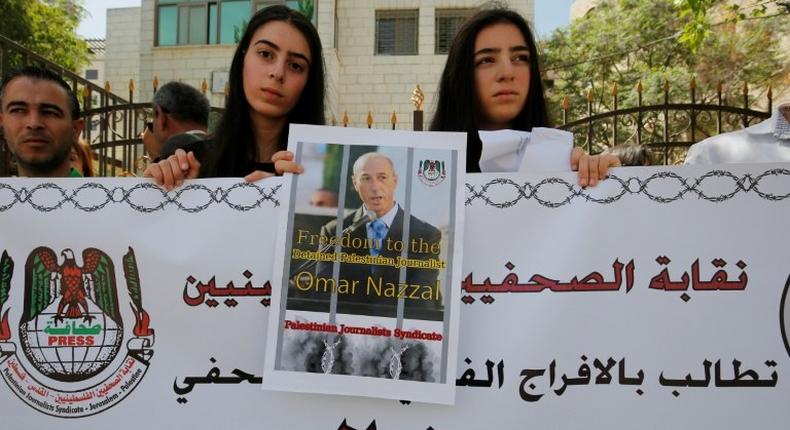 Palestinian journalists hold placards during a demonstration on April 24, 2016, outside the Red Cross offices in the West Bank city of Ramallah, in support of their colleague, Omar Nazzal, who was detained the previous day by Israeli forces
